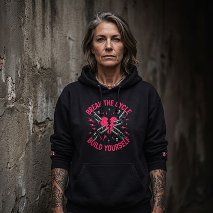 Woomen wearing a Break The Cycle Build Yourself black hoodie with a graphic design and text against a textured wall.