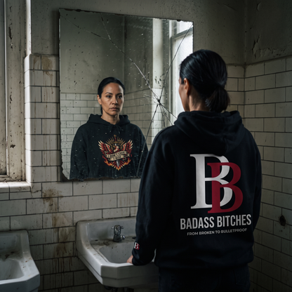 Women wearing a I Don't Chase I Rise hoodie with 'Badass Bitches' logo in a dilapidated bathroom.