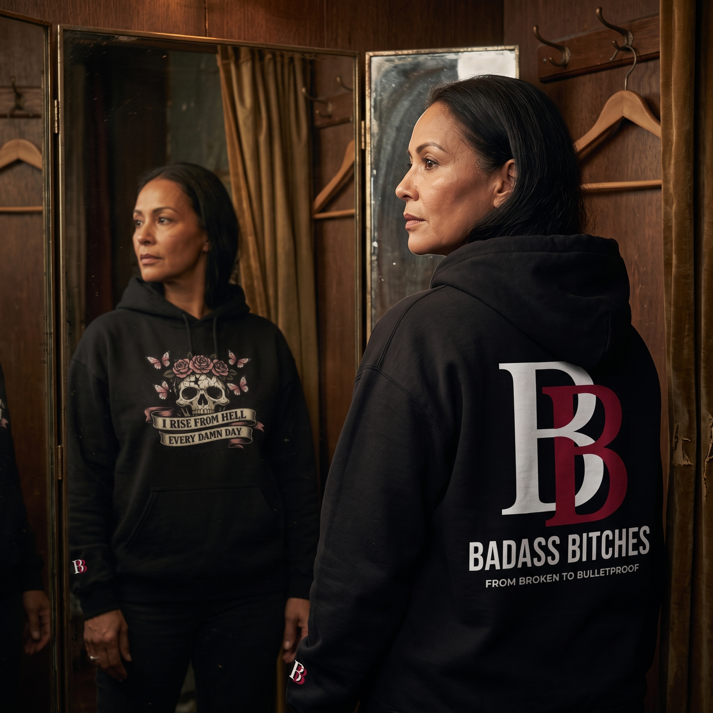 Women wearing black hoodie with "I Rise Frome Hell Every Damn Day" graphic and "Badass Bitches" logo, standing in a room with wooden walls and mirrors.