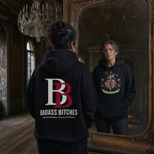 Women wearing a PTSD: People That See Different black hoodie with 'Badass Bitches'logo in a vintage room.