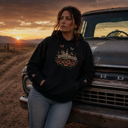 Woman in a "Pain Made Me A Problem" black hoodie leaning against an old truck with a sunset in the background