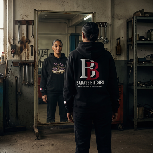 Women wearing a Pain Taught Me Power hoodie with 'Badass Bitches' logo in a workshop setting
