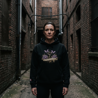 Women wearing a Pain Taught Me Power black hoodie with a graphic design in an alleyway.