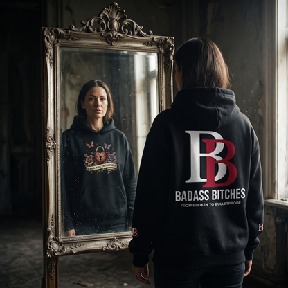 Women wearing a Scared Wild Unstoppable hoodie with 'Badass Bitches' logo, standing in front of a mirror.