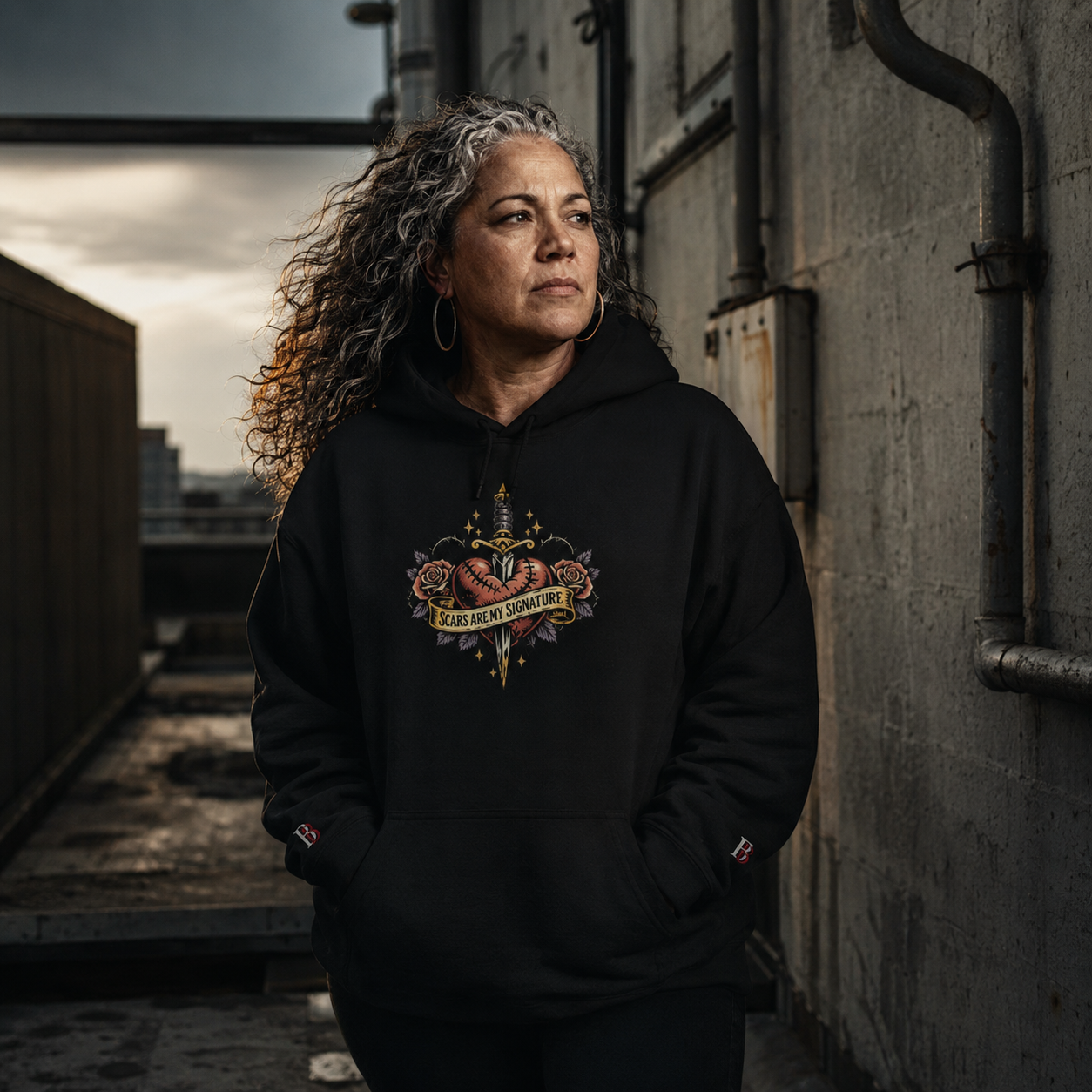Women wearing a Scars Are My Signature black hoodie with a graphic design in an urban setting