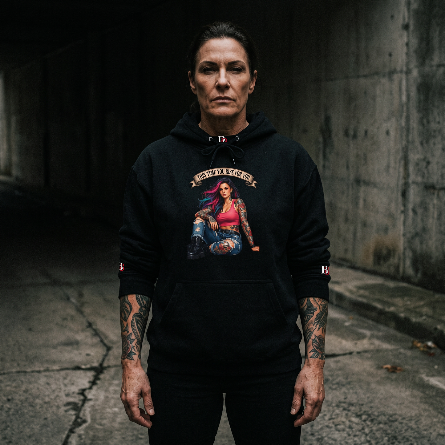 Women wearing a This Time You Rise For You black hoodie with a graphic design in an urban setting