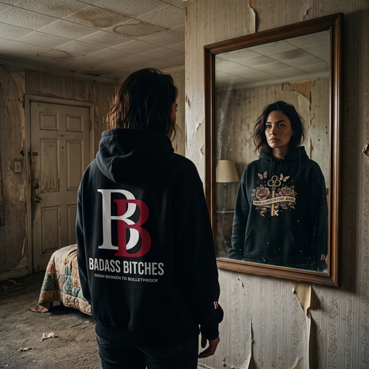 Person wearing a hoodie with "You're allowed to start again" graphic and 'Badass Bitches' logo on back in a dilapilated room